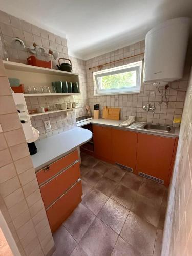 a kitchen with orange cabinets and a sink and a window at Hegylakó vendégház in Balatonkenese