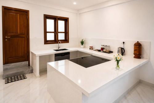 a white kitchen with a sink and a counter top at Nine Gems villa in Kandy