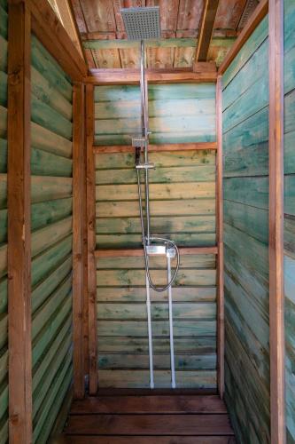 eine Dusche in einer Hütte mit Holzwänden in der Unterkunft Camping OR in Bucureşci
