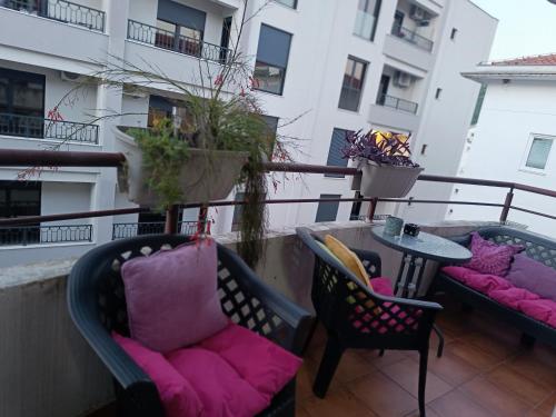 a balcony with two chairs and a table with pink pillows at Budva apartman Haustor in Budva