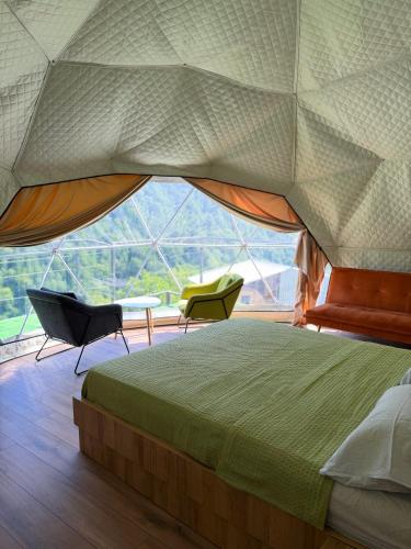 a bedroom with a bed and a large window at Mtirala Glamping in Ch'ak'vist'avi