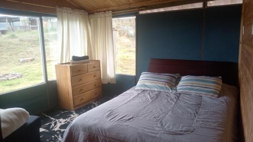 a bedroom with a bed and a dresser and windows at Luna Llena in Suesca