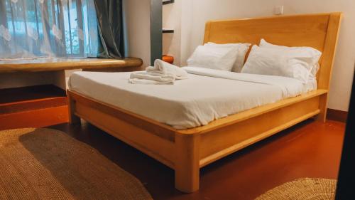 a bedroom with a wooden bed with white sheets and pillows at Unique Homestay in Karatu