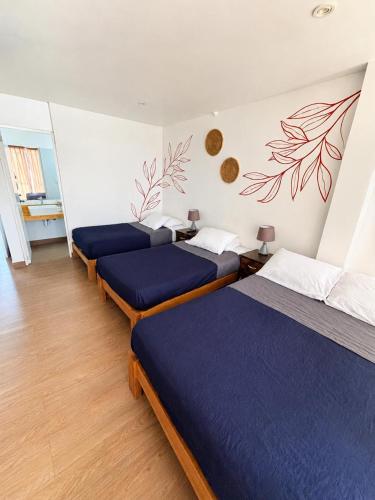three beds in a room with blue sheets at Killamoon House Paracas in Paracas