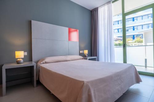 a bedroom with a bed and a large window at Apolo Suites Rentalmar in Salou
