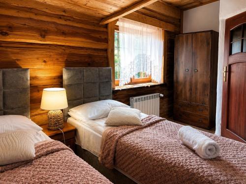 two beds in a room with wooden walls at Troll in Cisna