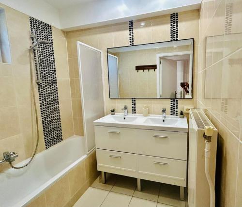 a bathroom with a sink and a mirror and a tub at Brussels Expo & Atomium Prestige Suites in Grimbergen