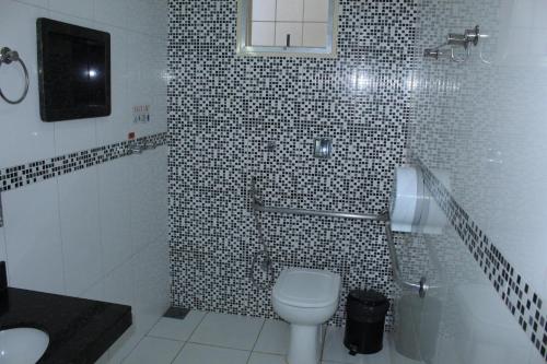 a bathroom with a toilet and a tiled shower at Via Hotel in Monte Alegre de Minas