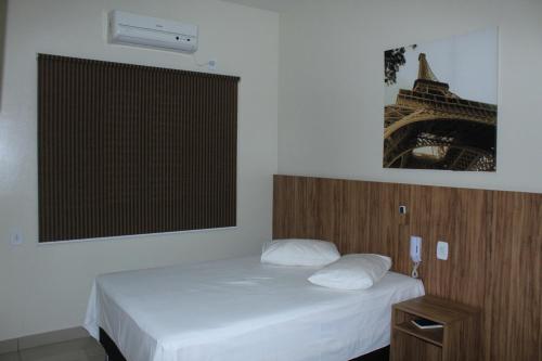 a bedroom with a bed and a picture of the eiffel tower at Via Hotel in Monte Alegre de Minas
