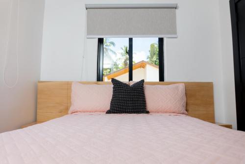 a bed with pink and black pillows and a window at Solaris Villa in Las Terrenas