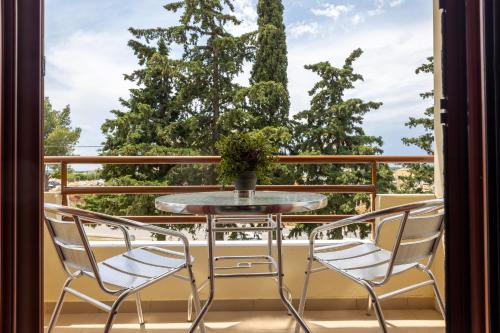 a table and chairs on a balcony with a window at Casa Stefanos in Afitos