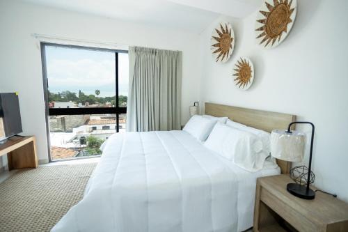 a bedroom with a white bed and a large window at Suites Santa Isabella in Ajijic