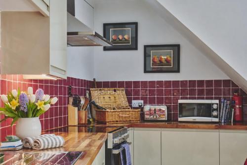 a kitchen with red tiled walls and a counter at Rathbone Cottage in Stow on the Wold