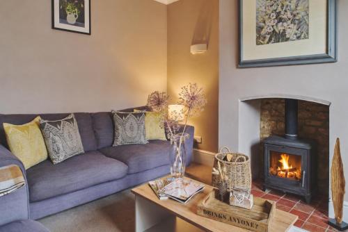 a living room with a couch and a fireplace at Rathbone Cottage in Stow on the Wold