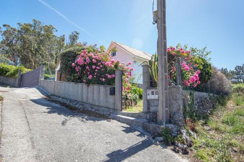 a house with pink flowers on a fence at AG Casa Camariñas, con jardín y vistas al mar in Camariñas