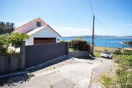 a house with a fence in front of the ocean at AG Casa Camariñas, con jardín y vistas al mar in Camariñas