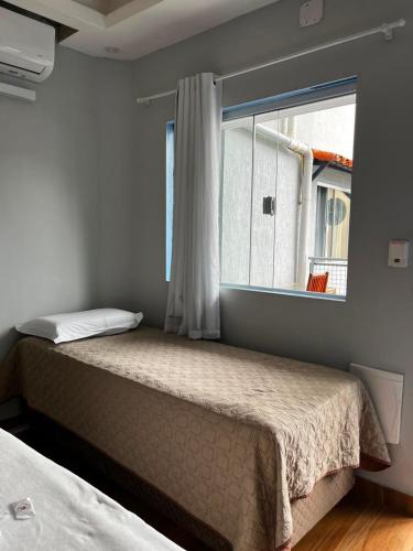 a bedroom with two beds and a window at Pousada Caravela in Arraial do Cabo