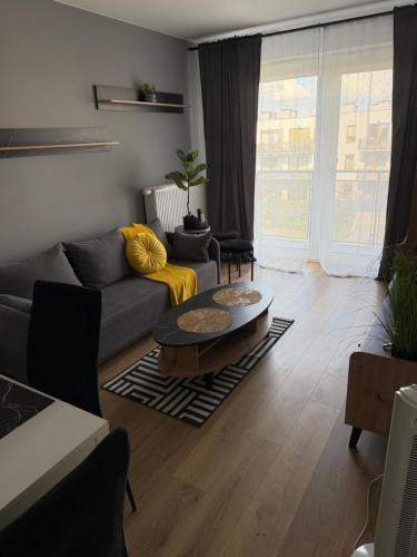a living room with a couch and a table at Apartament Grey 2 pokojowy z balkonem w Warszawie z parkingiem podziemnym in Warsaw