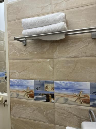 a bathroom with a towel rack with pictures on the wall at KuneVain Guest House in Lezhë