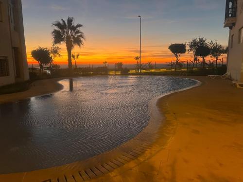 a pool of water with a sunset in the background at Marina Golf 7 in Asilah