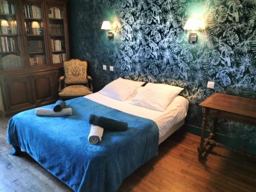 a bedroom with a bed with a blue blanket and a chair at Gîte du Domaine du Moulin de la Roque in Castels