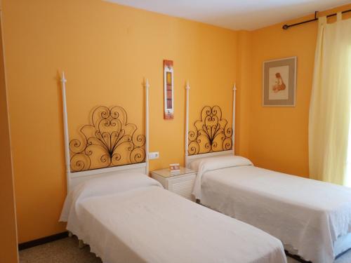 two beds in a room with yellow walls at Costadaurada2000 Sunset Beach Cunit in Cunit