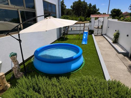 a large blue tub sitting on the grass with an umbrella at Holiday Home Marković in Bibinje