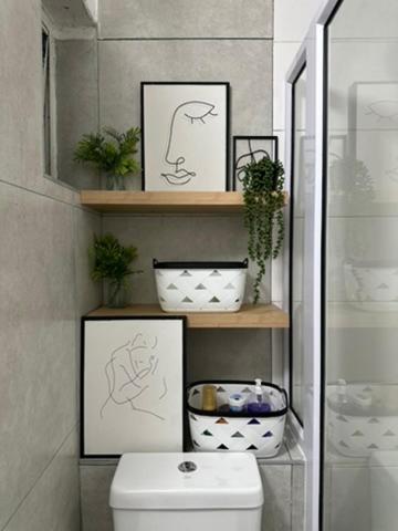 a bathroom with a toilet and some pictures on shelves at Home By The Sea in Gqeberha