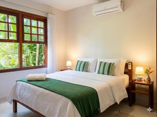 a bedroom with a large bed with a green blanket at Flat - SERRA E MAR - Paraty in Paraty