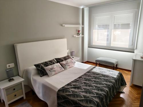 a bedroom with a bed with two pillows and a window at Arenales Azules in Baiona