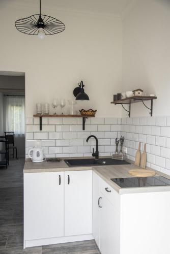 a kitchen with white cabinets and a sink at Víkend Apartmanok in Révfülöp