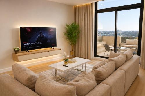 a living room with a large couch and a flat screen tv at Abha Elite Suites ابها ايليت سويتس in Abha