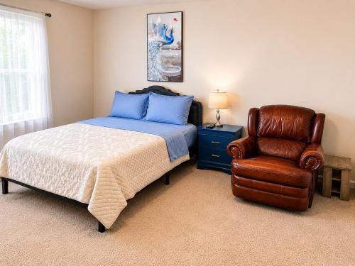 a bedroom with a bed and a leather chair at Guest House Haven with Gazebo in Riverdale