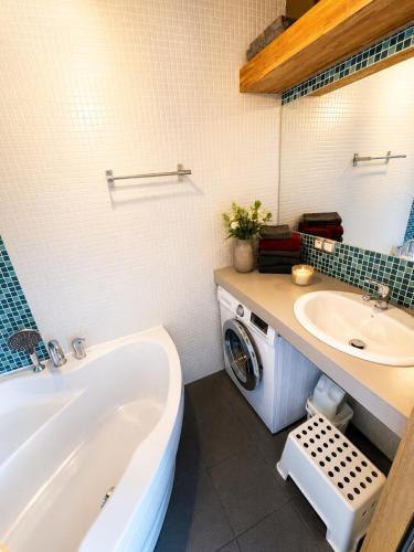 a bathroom with a tub and a sink and a washing machine at Like at home Brno - celý byt in Komárov