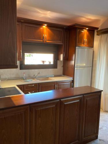 a kitchen with wooden cabinets and a white refrigerator at Villa Eleon 2 in Nea Vrasna