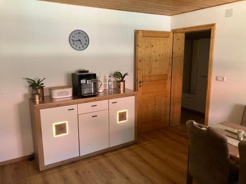a kitchen with white cabinets and a clock on the wall at Ferienwohnung Eble bei Markt Rettenbach in Markt Rettenbach