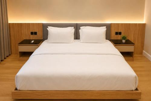 a large bed with white sheets and pillows at Abha Elite Suites ابها ايليت سويتس in Abha
