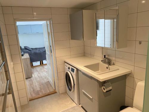 a bathroom with a sink and a washing machine at Centralt Semesterboende in Halmstad