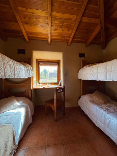 a room with two beds and a desk with a window at Posada La Tregua in El Bolsón