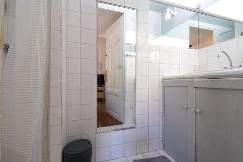 a white tiled bathroom with a sink and a mirror at LS7-468 - Eicela in Saint-Antonin-sur-Bayons