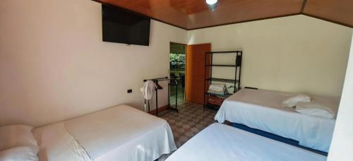 a room with two beds and a flat screen tv at Rancho Amigos Columbias Caldera in Esparza