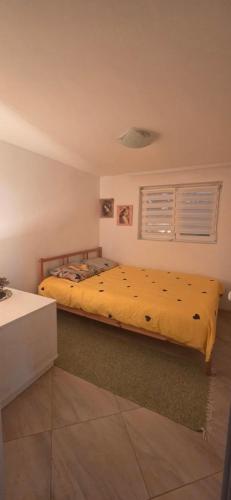 a bedroom with a bed with a yellow bedspread at Kod kapetana in Smederevo