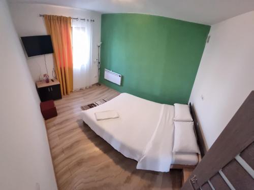 a bedroom with a white bed and a green wall at Casa Loredana in Cârțișoara