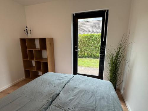 a bedroom with a bed and a door with a plant at Sortehus - 100 steps from the finest beach in Vallebo