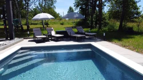 a swimming pool with chairs and tables and umbrellas at Country house Greenfields in Gospić