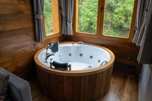 a bath tub in a room with two windows at Saffire Doğa Evleri in Güneyköy