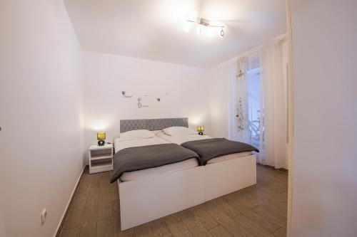 a white bedroom with a large bed and a window at Holiday Home Gabriela in Sukošan