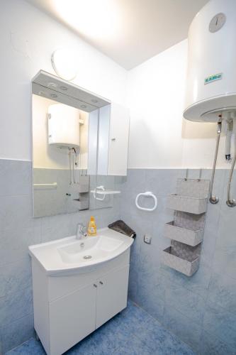 a white bathroom with a sink and a mirror at Holiday Home Gabriela in Sukošan