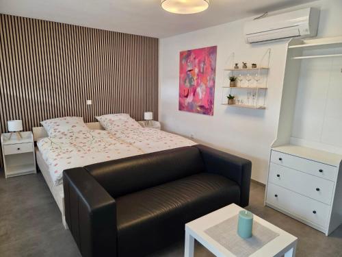 a bedroom with a bed and a black leather couch at Ferienhäuschen mit Wellnessbereich in Marsberg