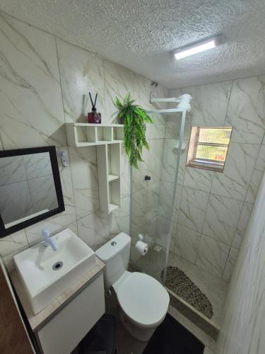 a bathroom with a toilet and a sink and a shower at Pousada Casa da arara Suite 106 in Saquarema